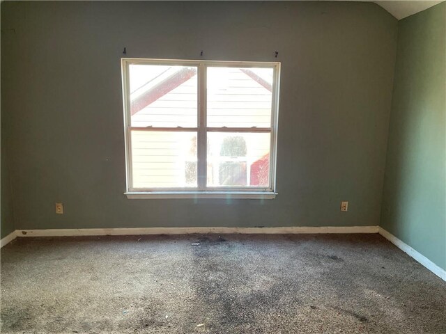 carpeted spare room with vaulted ceiling