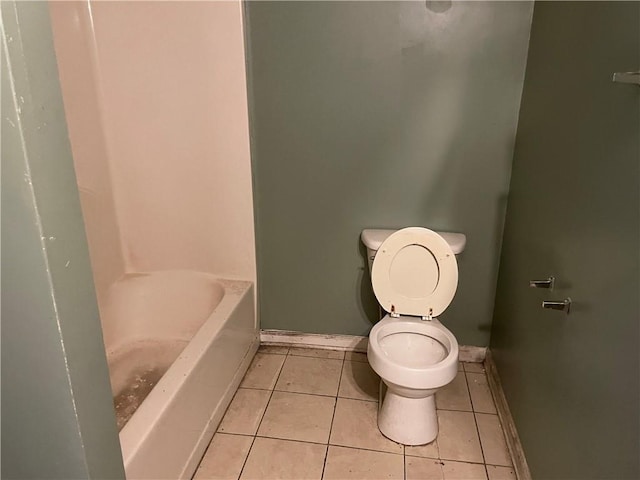 bathroom featuring tile patterned floors, toilet, and a tub to relax in