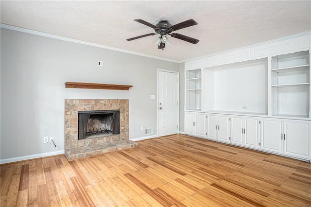 879 Rock Oak Ln, Lawrenceville, GA 30046 - unfurnished living room featuring light wood-style flooring, ceiling fan, baseboards, crown molding, and a stone fireplace