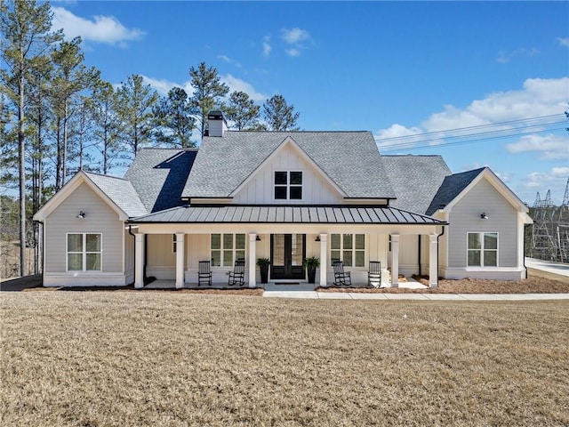 modern farmhouse featuring a standing seam roof, a front yard, board and batten siding, and a shingled roof