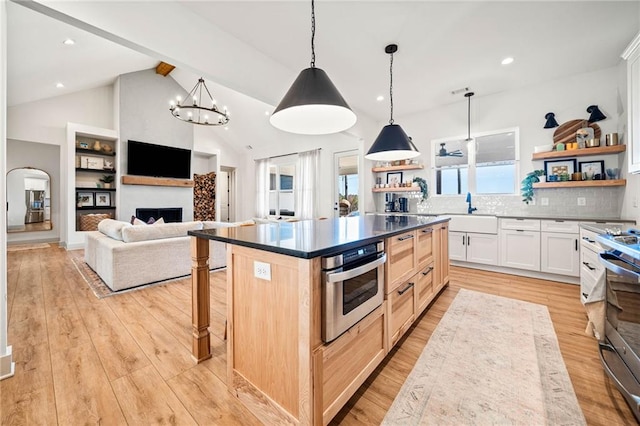 kitchen with open shelves, a sink, stainless steel appliances, a fireplace, and light wood finished floors