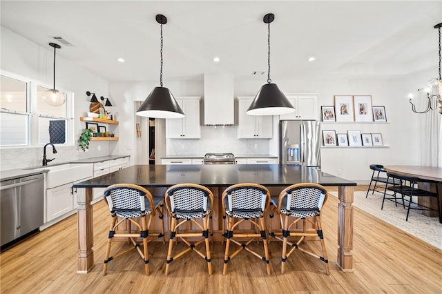 kitchen featuring premium range hood, appliances with stainless steel finishes, white cabinets, and a sink