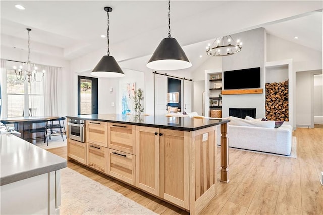 kitchen with a raised ceiling, dark countertops, light wood-style flooring, and light brown cabinets