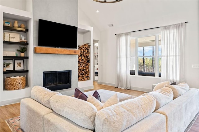 living room featuring visible vents, built in features, wood finished floors, a fireplace, and baseboards