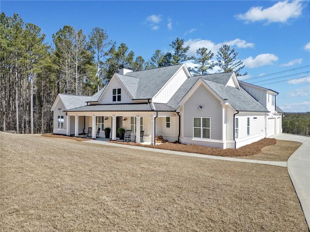 modern farmhouse with a garage, a standing seam roof, a porch, metal roof, and a chimney