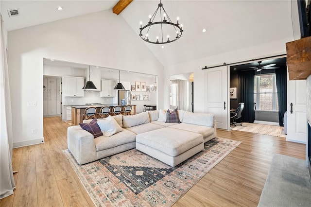 living area featuring visible vents, high vaulted ceiling, light wood-style flooring, a barn door, and beamed ceiling