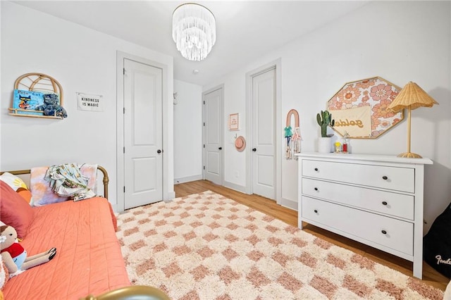 bedroom featuring baseboards, a notable chandelier, and wood finished floors