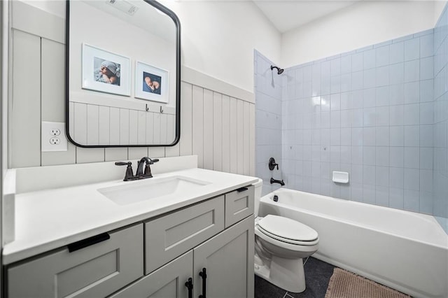 full bath featuring visible vents, a wainscoted wall, shower / washtub combination, toilet, and vanity