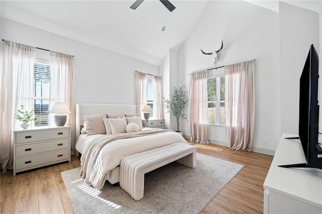 bedroom with light wood-style flooring, high vaulted ceiling, baseboards, and a ceiling fan