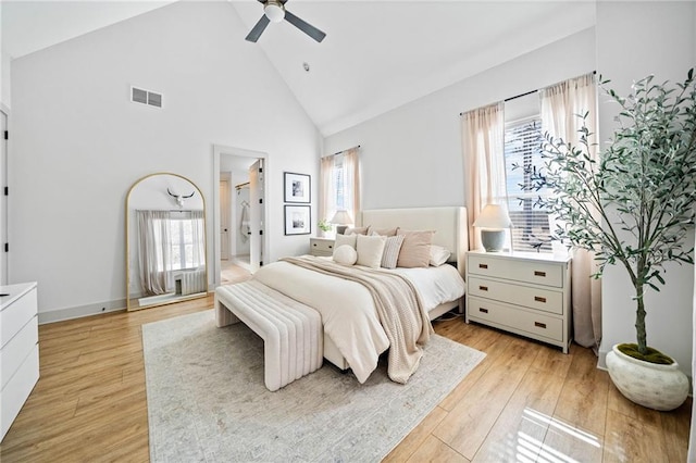 bedroom featuring visible vents, ceiling fan, ensuite bathroom, light wood-style floors, and high vaulted ceiling