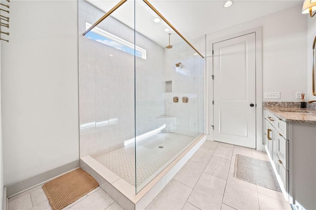 full bath featuring tile patterned floors, a tile shower, recessed lighting, baseboards, and vanity