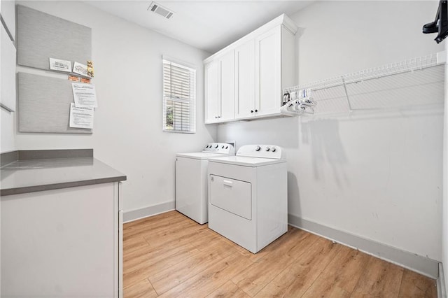 laundry room with visible vents, light wood finished floors, baseboards, separate washer and dryer, and cabinet space