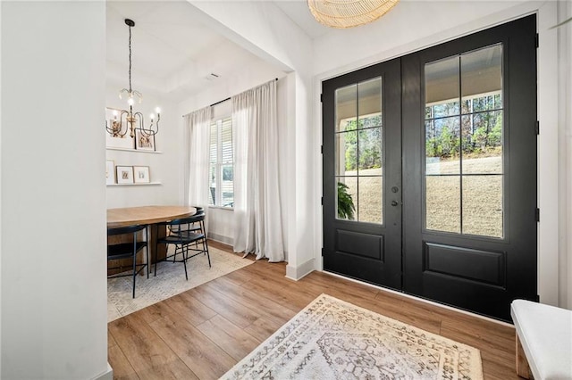 foyer entrance featuring a chandelier, french doors, baseboards, and wood finished floors