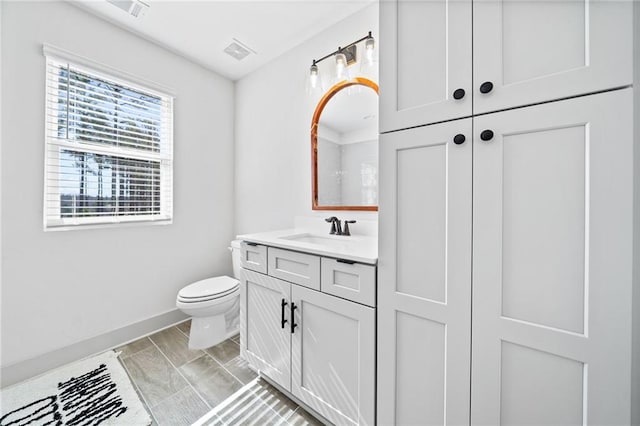 bathroom with visible vents, toilet, vanity, and baseboards