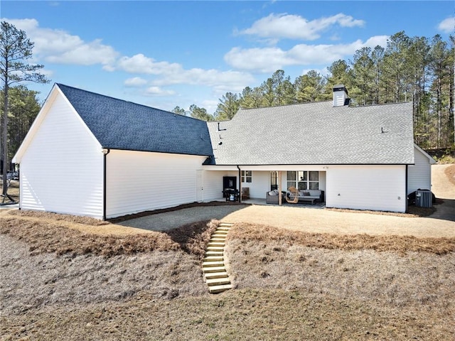 back of house with stairway, a patio, roof with shingles, and a chimney