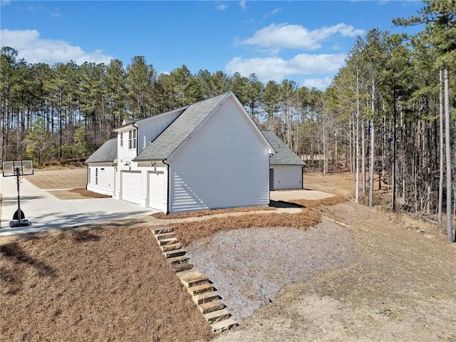 view of home's exterior featuring a garage, roof with shingles, and concrete driveway