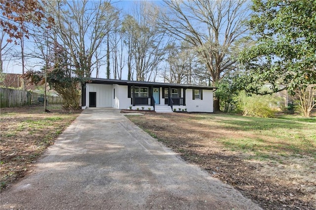 view of front facade featuring an attached carport, fence, a porch, a front yard, and driveway