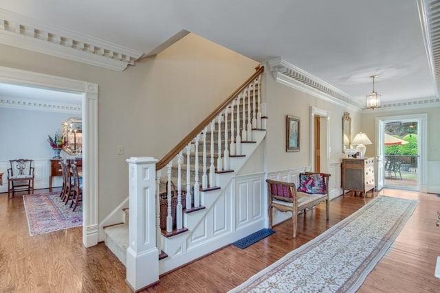 stairs featuring hardwood / wood-style flooring, a notable chandelier, and crown molding