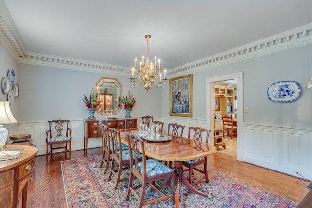 dining room with an inviting chandelier, crown molding, and wood-type flooring