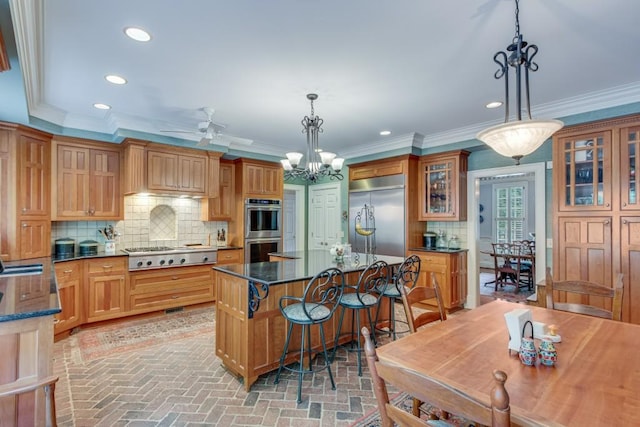 kitchen with a breakfast bar area, stainless steel appliances, hanging light fixtures, a center island, and decorative backsplash