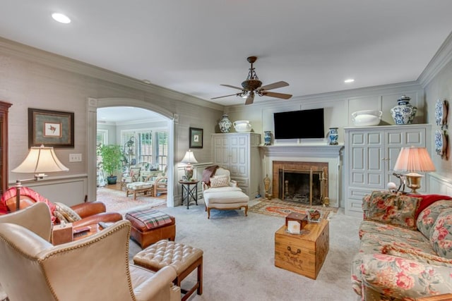 carpeted living room with ceiling fan and ornamental molding