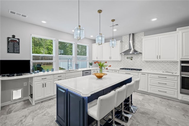 kitchen featuring visible vents, a sink, light countertops, stainless steel appliances, and wall chimney exhaust hood