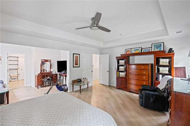 bedroom with visible vents, a raised ceiling, baseboards, and light wood-style floors