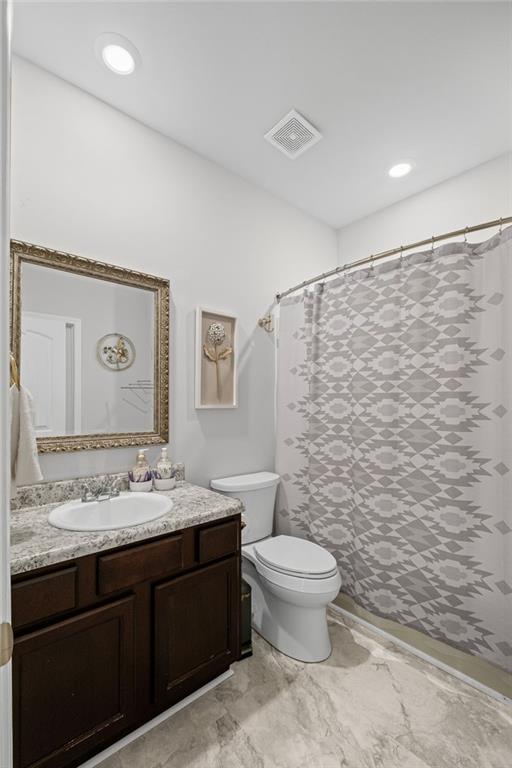 bathroom with visible vents, curtained shower, toilet, and vanity