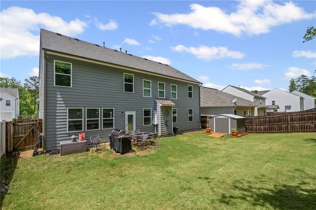 rear view of house with a storage shed, a lawn, an outdoor structure, and a fenced backyard