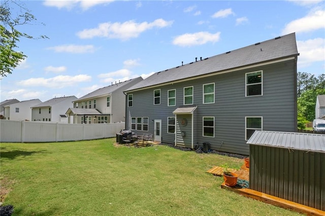 back of house featuring a lawn, fence, a residential view, and an outdoor structure