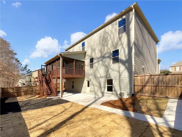 rear view of property with stairs, a patio area, fence, and a sunroom