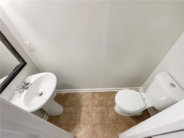 bathroom with toilet, baseboards, and a sink