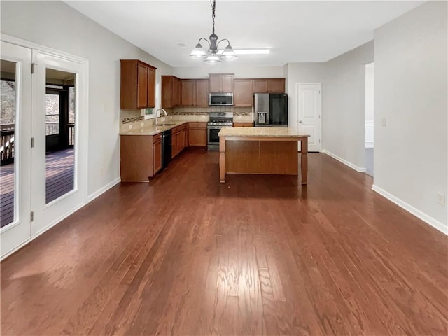 kitchen with brown cabinets, a center island, stainless steel appliances, pendant lighting, and a sink