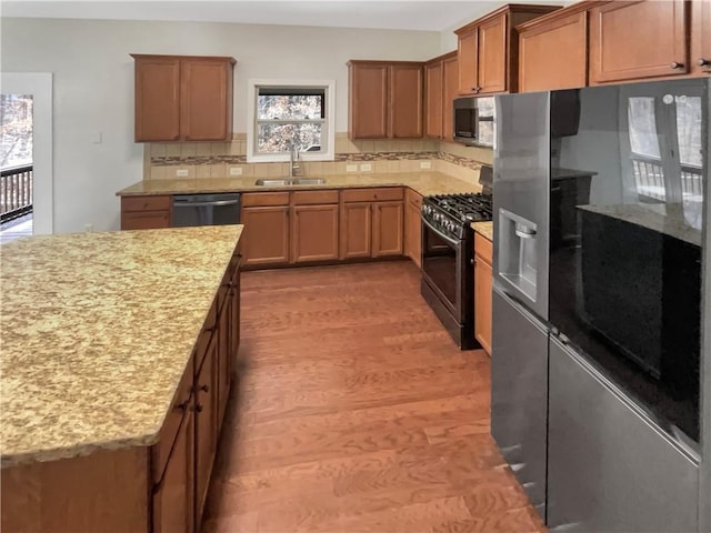 kitchen featuring appliances with stainless steel finishes, backsplash, a sink, and brown cabinetry