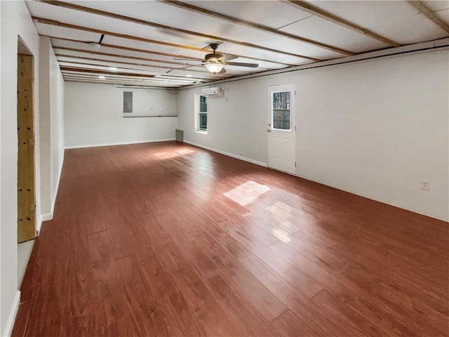 unfurnished living room with dark wood-style flooring, a ceiling fan, and baseboards