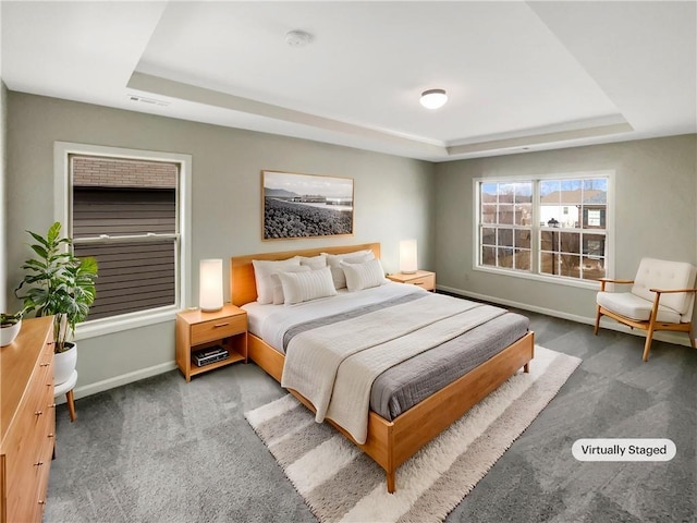 bedroom with baseboards, visible vents, a tray ceiling, and dark carpet