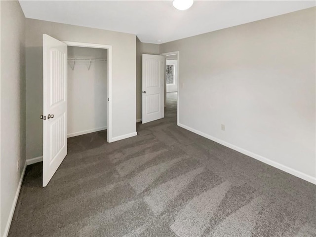 unfurnished bedroom with baseboards, dark carpet, and a closet