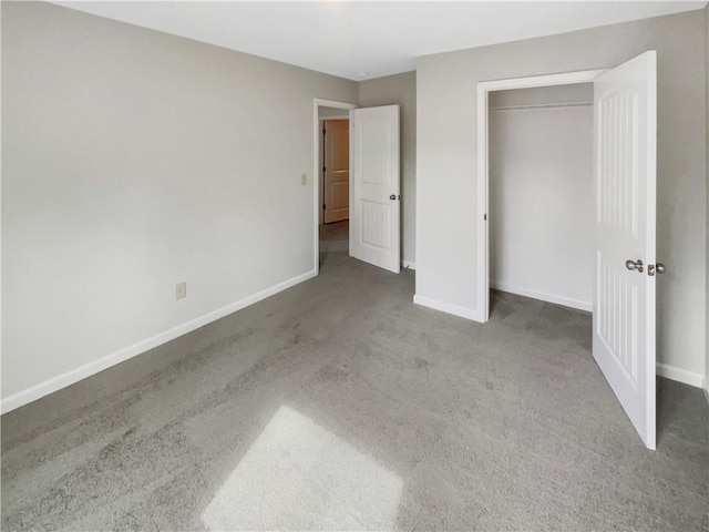 unfurnished bedroom featuring baseboards, dark colored carpet, and a closet