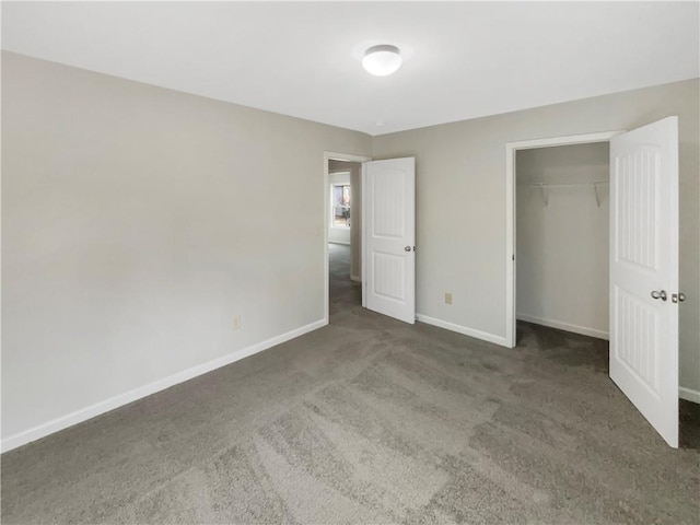 unfurnished bedroom featuring dark colored carpet, a closet, and baseboards