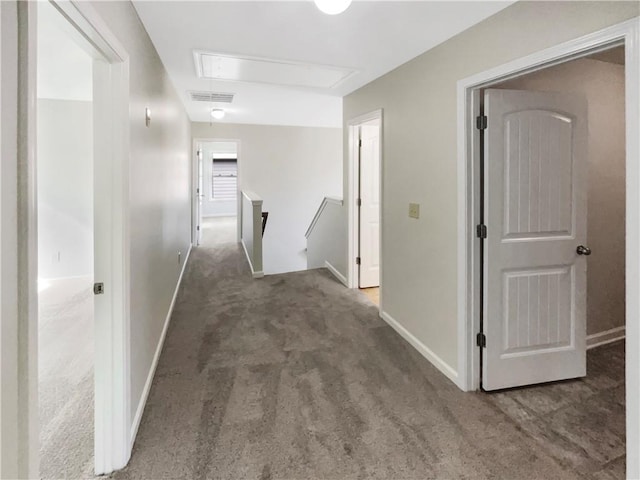 hall with dark colored carpet, visible vents, attic access, an upstairs landing, and baseboards