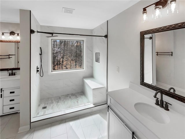 bathroom with a marble finish shower, visible vents, and vanity