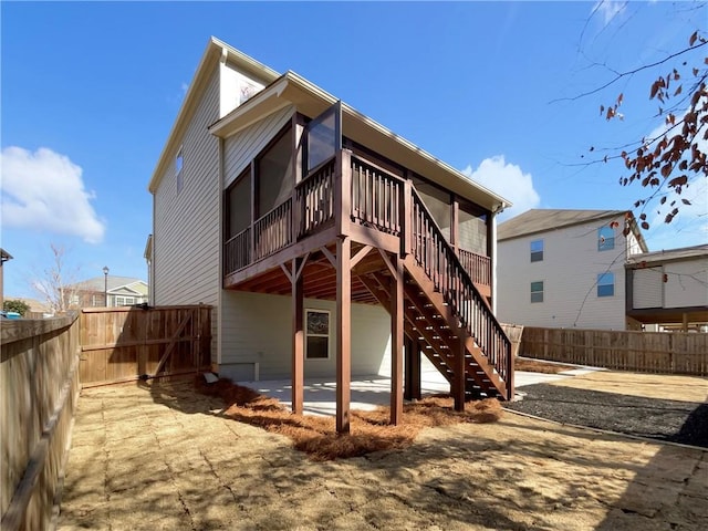 rear view of property featuring a fenced backyard, stairway, a wooden deck, and a patio