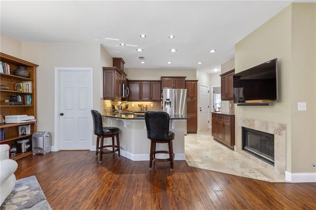 2905 Ivey Ridge Ln, Roswell, GA 30076 - kitchen with a peninsula, hardwood / wood-style floors, dark countertops, stainless steel fridge with ice dispenser, and a breakfast bar