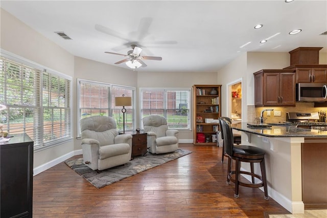 2905 Ivey Ridge Ln, Roswell, GA 30076 - kitchen with stainless steel appliances, a breakfast bar, a ceiling fan, dark stone countertops, and dark wood finished floors