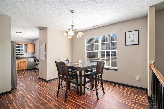 dining room featuring an inviting chandelier, a textured ceiling, and dark hardwood / wood-style floors