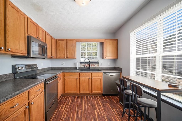 kitchen featuring a textured ceiling, sink, dark wood-type flooring, and stainless steel appliances