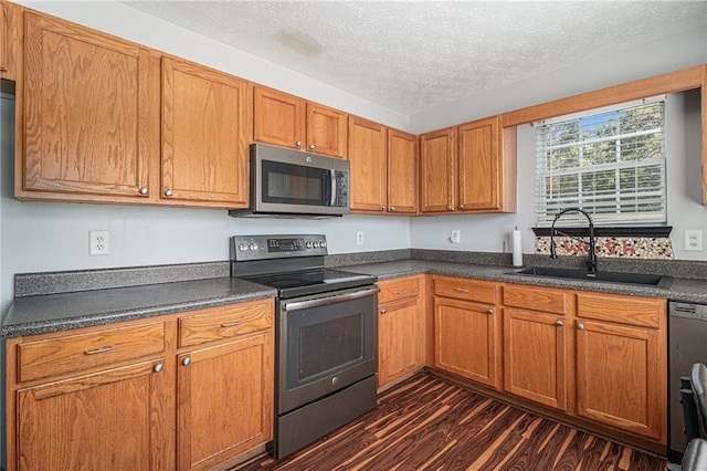 kitchen with a textured ceiling, sink, stainless steel appliances, and dark hardwood / wood-style flooring