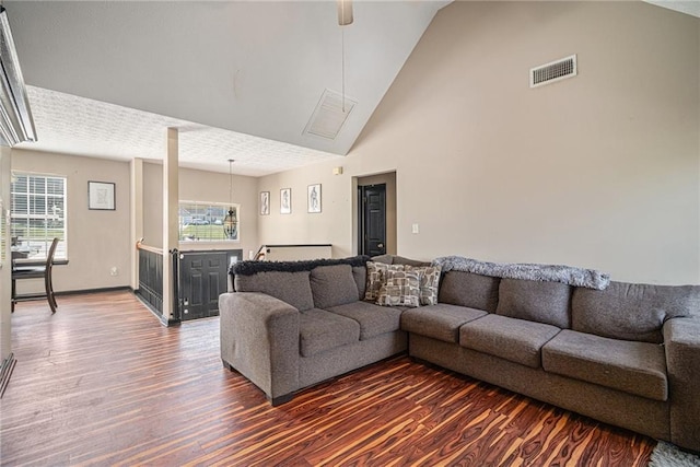 living room with a textured ceiling, dark wood-type flooring, and high vaulted ceiling