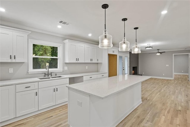 kitchen featuring white cabinets, ceiling fan, sink, and a fireplace