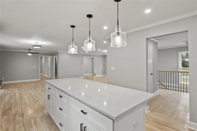 kitchen featuring light stone countertops, ceiling fan, white cabinets, a center island, and hanging light fixtures